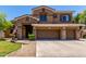 Two-story home with a three-car garage, stone accents, manicured lawn, and covered entryway at 723 E Gemini Pl, Chandler, AZ 85249