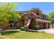 Two-story house with stone accents, spacious front yard, mature trees, and a three-car garage at 723 E Gemini Pl, Chandler, AZ 85249