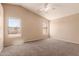 Spacious bedroom with neutral carpet, ceiling fan, and windows for natural light at 7419 W Raymond St, Phoenix, AZ 85043