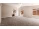 Spacious living room with neutral carpet, ample natural light, and seamless flow to kitchen at 7419 W Raymond St, Phoenix, AZ 85043