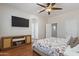 Bedroom showcases a sleek TV mounted above a wooden cabinet and a comfortable bed with floral bedding at 7736 W Tumblewood Dr, Peoria, AZ 85382