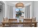 Elegant dining room with a wooden table, six chairs, modern chandelier, and a bay window view at 7736 W Tumblewood Dr, Peoria, AZ 85382