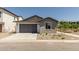 Home features low maintenance desert landscaping, gray two-car garage and a concrete driveway at 9416 E Sequence Ave, Mesa, AZ 85212