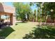 Large backyard featuring a covered patio, mature trees, and a glimpse of the fenced pool area at 111 N Soho Pl, Chandler, AZ 85225