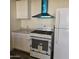 Bright kitchen featuring white cabinets, appliances, and a modern vent hood at 11411 N 91St Ave # 188, Peoria, AZ 85345