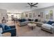 Spacious living room with light wood floors, a large sofa, a ceiling fan, and a view of the kitchen at 12236 W Country Club Ct, Sun City, AZ 85373