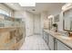 A luxurious bathroom featuring double sinks, granite countertops, tile flooring, and a stone-tiled walk-in shower at 15532 W Prairie Dunes Dr, Surprise, AZ 85374