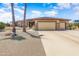 Charming home featuring a three-car garage, stone accents, and a meticulously landscaped front yard under a bright blue sky at 15532 W Prairie Dunes Dr, Surprise, AZ 85374