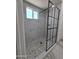 Modern walk-in shower featuring striking black-framed glass, decorative pebble floor, and white tiled walls at 1627 W Pueblo Ave, Mesa, AZ 85202