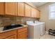 Laundry room with wooden cabinets, countertop and backsplash, sink, washer and dryer at 16781 W Northampton Rd, Surprise, AZ 85374
