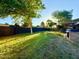 Large backyard featuring green grass, tall trees and a dark wooden fence at 1742 W Butler Dr, Phoenix, AZ 85021