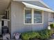 Close up of the home featuring a window with blinds, trimmed landscaping, and the house number 121 at 2233 E Behrend Dr # 121, Phoenix, AZ 85024