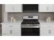 Close up on kitchen range and hood, with white cabinets and neutral tile backsplash at 3310 E Valleyhigh Trl, San Tan Valley, AZ 85143