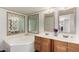 Primary bathroom featuring double sinks, a soaking tub and decorative mirrors at 48773 Cerezo Rd # 20, Maricopa, AZ 85139