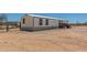 Mobile home featuring a small front porch, set in a desert landscape with utility connections at 48773 Cerezo Rd # 20, Maricopa, AZ 85139