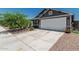 Home's exterior showcasing a wide driveway, gray siding, white garage door, and manicured landscaping at 5709 S 13Th Ave, Phoenix, AZ 85041