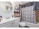 Full bathroom features a classic white vanity, mirror, and a shower-tub combo with a stylish curtain at 5807 W Encanto Blvd, Phoenix, AZ 85035