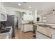 Open kitchen showcases white cabinets, stainless steel appliances, tile flooring, and a breakfast bar overlooking the living area at 609 S 122Nd Dr, Avondale, AZ 85323