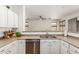 Bright kitchen features white cabinetry, a stainless steel dishwasher, tile flooring, and a view into the living area at 609 S 122Nd Dr, Avondale, AZ 85323