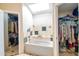 Bathroom showcasing a soaking tub under a skylight, with walk-in closets on either side at 7725 W Dreyfus Dr, Peoria, AZ 85381