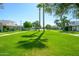 Expansive green common area surrounded by single story homes with palm trees in a well-maintained community at 8341 E Keim Dr, Scottsdale, AZ 85250