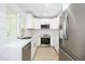 Kitchen boasts stainless steel appliances, white cabinetry, white counters, and new hardwood flooring at 8341 E Keim Dr, Scottsdale, AZ 85250