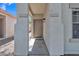 Covered entryway with neutral columns and a solid wood front door at 9261 W Sheridan St, Phoenix, AZ 85037