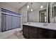 Bathroom featuring dual sinks, modern lighting, tile floor and a shower-tub with striped curtain at 9437 W Georgia Ave, Glendale, AZ 85305