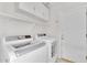 Well-lit laundry room features white appliances, overhead cabinets, and convenient shelving for storage at 10304 E Plata Ave, Mesa, AZ 85212