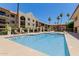 Sparkling community pool and spa area with lounge chairs, umbrellas, and palm trees at 10330 W Thunderbird Blvd # C109, Sun City, AZ 85351