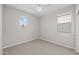 An empty bedroom with neutral carpet, a ceiling fan and two windows with white trim and a view at 13465 N 158Th Ave, Surprise, AZ 85379