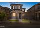 Charming two-story home at twilight featuring a cozy front porch with stone accents and a well-manicured front yard at 13465 N 158Th Ave, Surprise, AZ 85379