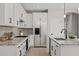 Bright kitchen featuring white cabinets, granite counters, gray backsplash, stainless steel appliances, and dark hardware at 13465 N 158Th Ave, Surprise, AZ 85379