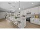 Open concept kitchen with white cabinets, granite countertops, island sink, and view into the adjacent dining and living areas at 13465 N 158Th Ave, Surprise, AZ 85379