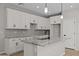 Kitchen with white cabinets, granite countertops, stainless steel appliances, gray backsplash, and island sink at 13465 N 158Th Ave, Surprise, AZ 85379