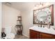 A simple bathroom featuring a toilet and vanity, with a decorative mirror and display shelf at 14622 N 45Th Pl, Phoenix, AZ 85032