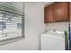 Practical laundry room features upper cabinets, a dryer, and a bright window at 14885 W Ashland Ave, Goodyear, AZ 85395