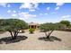 Landscaped backyard with decorative gravel and mature shade trees, creating a tranquil outdoor space at 17009 W Eureka Springs Dr, Surprise, AZ 85387
