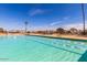 An expansive community pool with multiple lanes for swimming, under a clear sky with palm trees at 17200 W Bell Rd # 2162, Surprise, AZ 85374