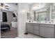 Bathroom with gray cabinets, double sinks, and view to bedroom at 17338 W Via De Luna Dr, Surprise, AZ 85387
