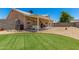 Backyard featuring manicured grass, desert landscaping, and covered patio with picnic table at 2018 N 104Th Dr, Avondale, AZ 85392