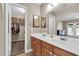 Bathroom featuring double sinks, wooden cabinets, and a view to the walk-in closet and bedroom at 2324 E Crescent Ave, Mesa, AZ 85204