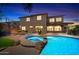 Night view of the backyard featuring a pool with spa, built-in fire pit, and basketball court at 2541 E Carob Dr, Gilbert, AZ 85298