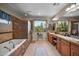 Bright bathroom featuring double sinks, bathtub and walk-in shower with large window view of backyard trees at 2541 E Carob Dr, Gilbert, AZ 85298
