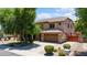 Suburban home boasting mature landscaping, a spacious driveway, and a warm, inviting facade in the sun at 2541 E Carob Dr, Gilbert, AZ 85298