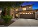 Beautiful home featuring a manicured lawn, stone accents, and a spacious driveway and garage in the evening at 2541 E Carob Dr, Gilbert, AZ 85298