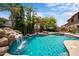 Backyard pool featuring a rock waterfall and surrounded by lush tropical landscaping at 2541 E Carob Dr, Gilbert, AZ 85298