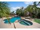 Backyard pool and hot tub area featuring a rock waterfall and lush tropical landscaping at 2541 E Carob Dr, Gilbert, AZ 85298