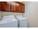 Functional laundry room features washer, dryer and wooden cabinets for storage at 26505 N Babbling Brook Dr, Phoenix, AZ 85083