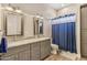 Updated bathroom features double sinks, granite countertop, wood tile floor, and a shower with blue curtain at 28156 N Edwards Rd, San Tan Valley, AZ 85143